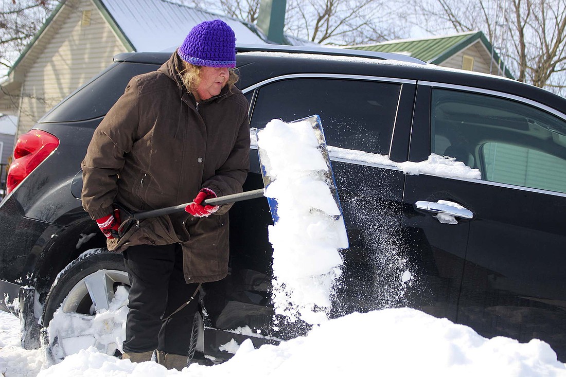 Jeana Clayton clears snow from under the tires of a vehicle Thursday morning along Shank Street on the south side of Portland. Conditions were improving throughout the area Wednesday and Thursday morning as winds had calmed down enough to allow plowing crews to hold on to their progress after blowing and drifting snow had caused problems Tuesday. (The Commercial Review/Bailey Call)